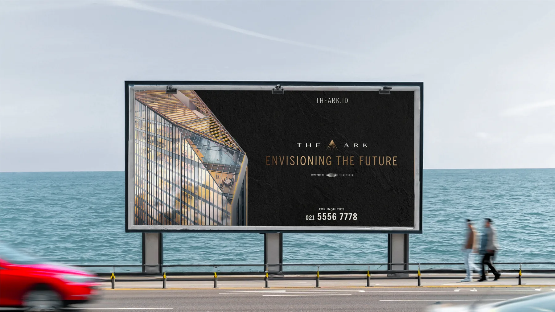 The Ark billboard “Envisioning the future” beside a seaside road with a red car passing