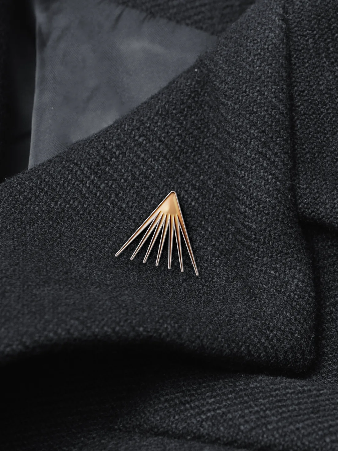 Copper ray logogram pin on the lapel of a black jacket