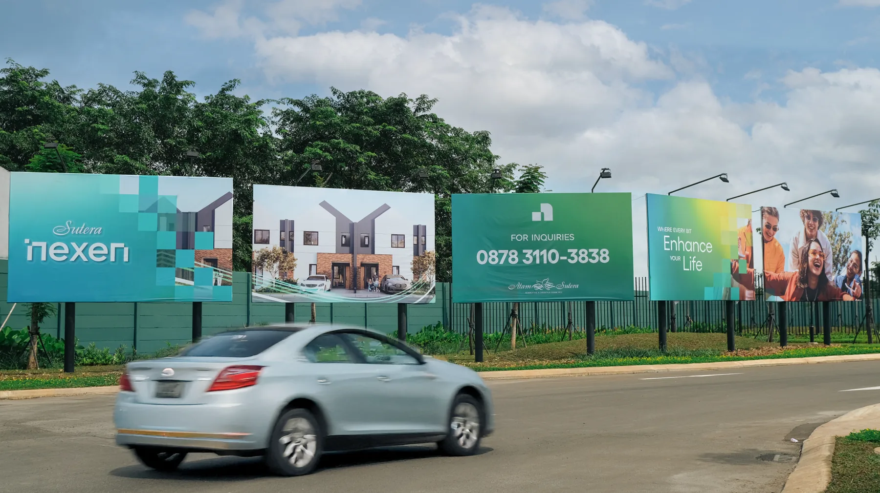 Four Nexen billboards beside a road with a car passing