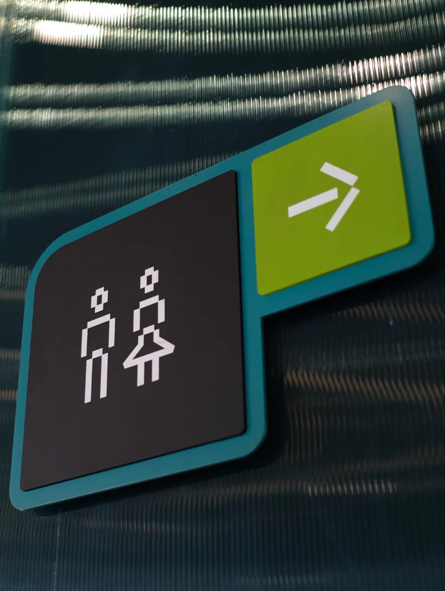 Restroom sign with person icons and a green arrow