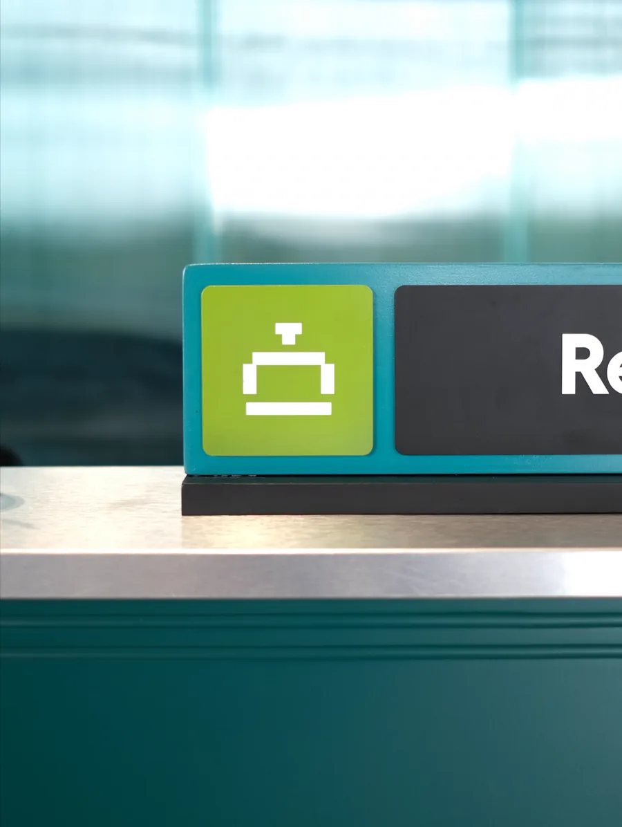 Reception sign with a bell icon above a teal counter