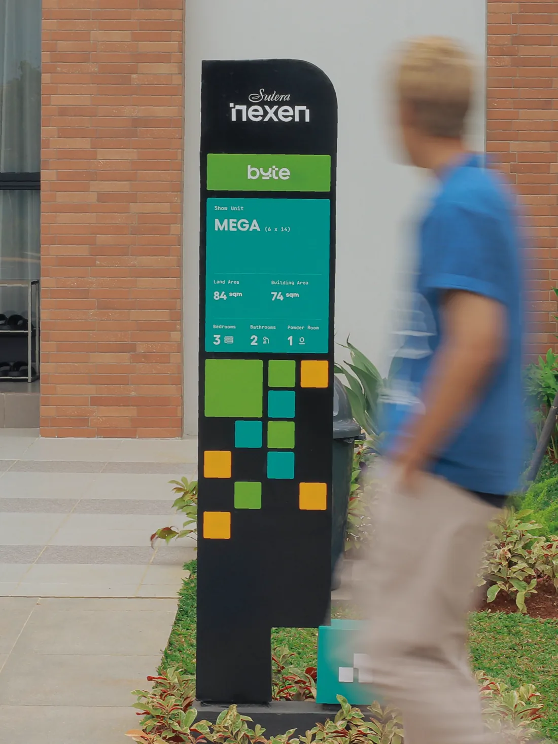 Passer-by in a blue shirt walking beside a tall unit sign
